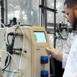 Investigador de la PUCV junto a un biorreactor de laboratorio para producir biohidrógeno