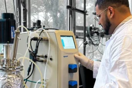 Investigador de la PUCV junto a un biorreactor de laboratorio para producir biohidrógeno