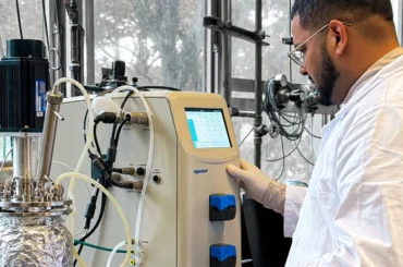 Investigador de la PUCV junto a un biorreactor de laboratorio para producir biohidrógeno