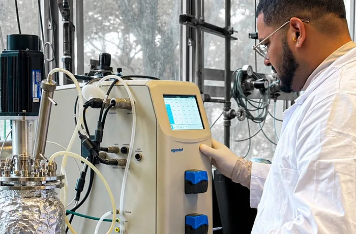 Investigador de la PUCV junto a un biorreactor de laboratorio para producir biohidrógeno
