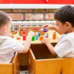 Niños pequeños jugando con juguetes de madera en la sala de un jardín infantil