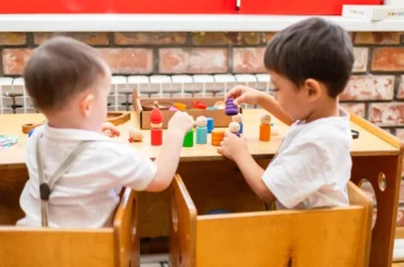 Niños pequeños jugando con juguetes de madera en la sala de un jardín infantil